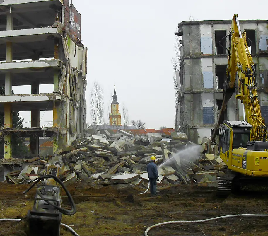 Bagger und Bauarbeiter vor abbruchreifen Gebäuden in Brandenburg