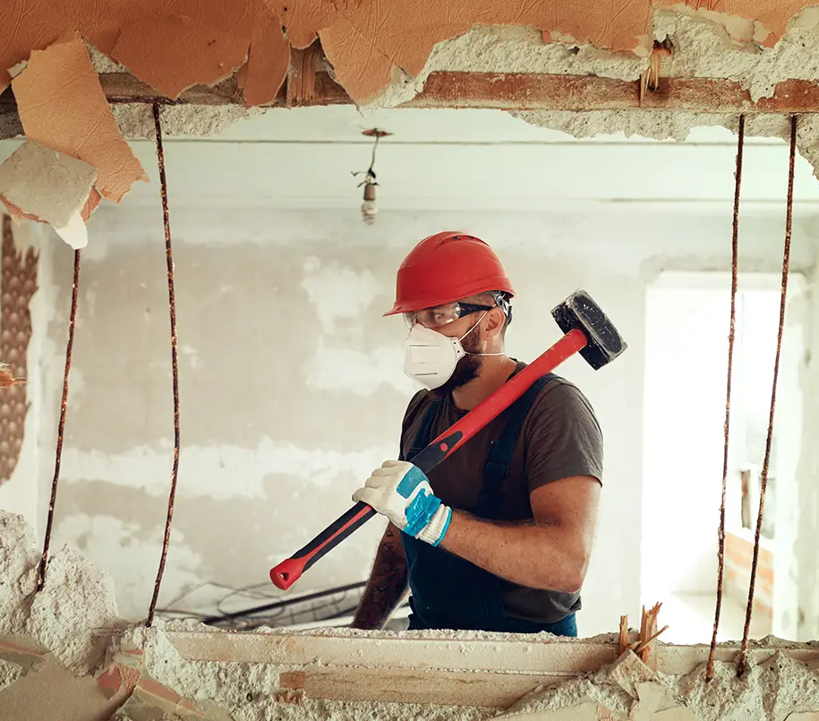 Bauarbeiter mit Vorschlaghammer beim Durchbrechen einer Wand
