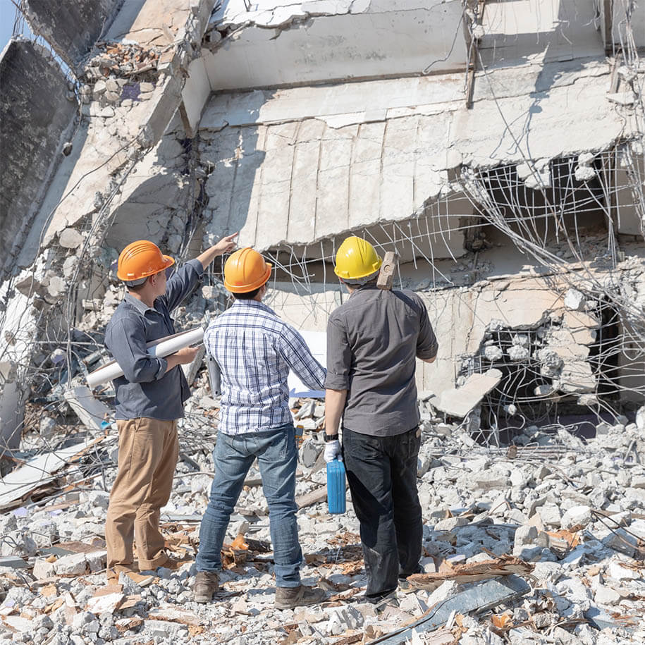 Drei Bauarbeiter bei der Planung und Überwachung des Abrisses vor einem Abbruchhaus