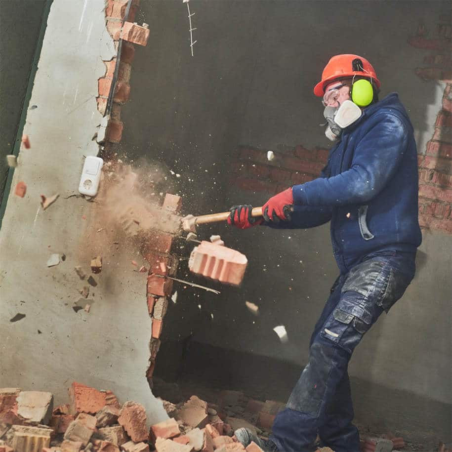 Arbeiter beim Abriss einer Wand mit dem Vorschlaghammer.