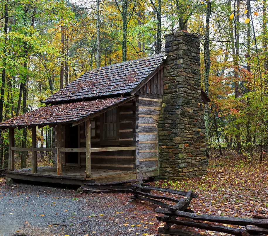 Verrottete Hütte mit steinernem Kamin und Veranda im Wald