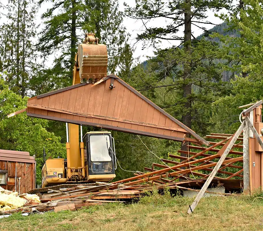 Bagger beim abriss eines alten Holzhauses